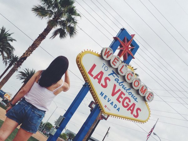 woman standing by welcome to las vegas sign